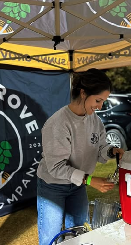 Team member pouring beer at a Sunny Grove pop-up tent