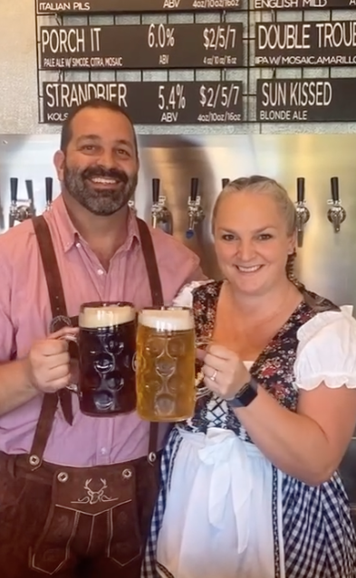 Two people cheering with large beer steins in festive Octoberfest attire